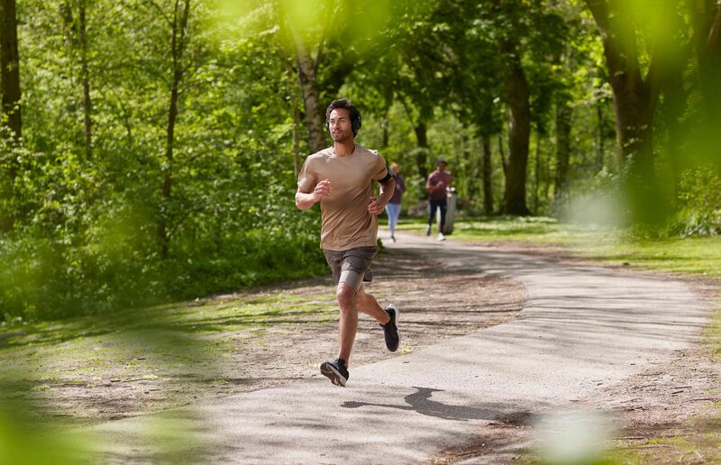 Man running in a park with green trees